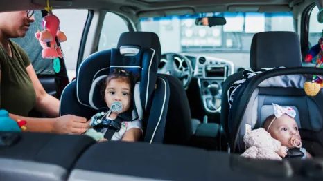 Mom safely buckling kids into their car seats following car seat safety guidelines