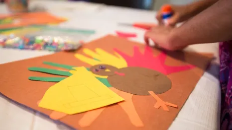 Child's hands making Thanksgiving turkey craft