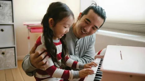 Dad and daughter sitting at a small piano gratitude activities kids