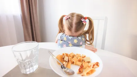 young girl experiencing challenges at a family dinner table 