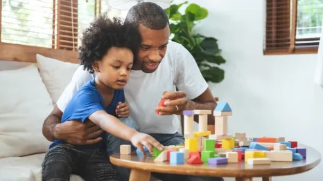 Dad and son having positive experience together playing with blocks on a table