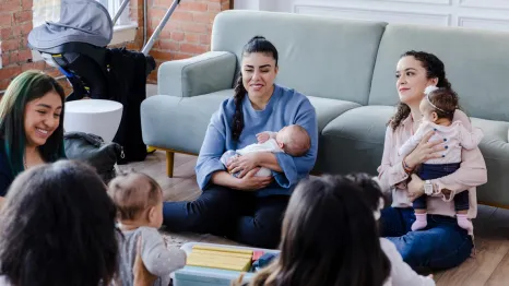 New moms sitting in a living room together connecting as new parents 