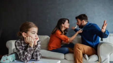 parents arguing in the background while a little girl is stressed in the foreground