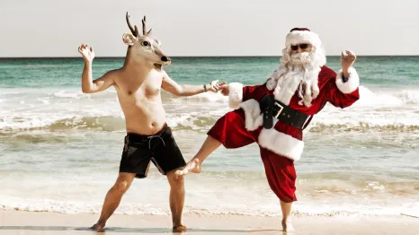 santa dancing with a reindeer on the beach