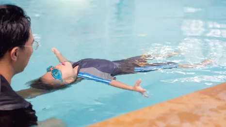 Boy floating in the water on his back in a swimming lesson