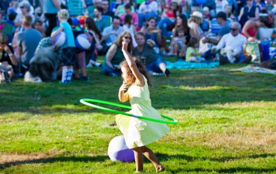 Girl plays with hula hoop at a Seattle summer concert on a sunny day