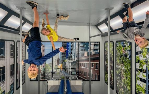 Three kids seemingly hang upside down in a reversed room at Museum of Illusions Seattle