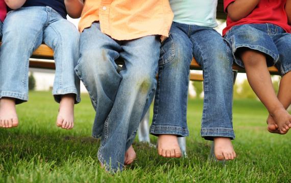 Young children sitting on a bench in the grass all wearing jeans. Target Denim Take Back Event
