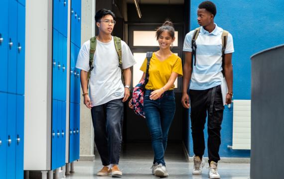 Three high school students walking down a school hallway