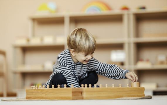 child plays in a Montessori playroom featuring low shelves and simple toys