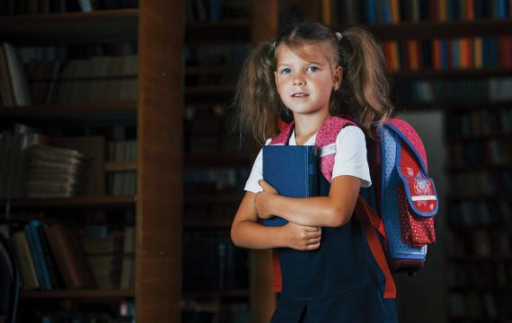 Young girl wearing a backpack getting ready to go to school