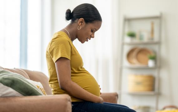 Pregnant woman looks down at her stomach