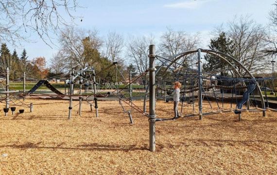 Young kid climbs on a rope bridge at a Seattle playground, on of the many things to do this weekend