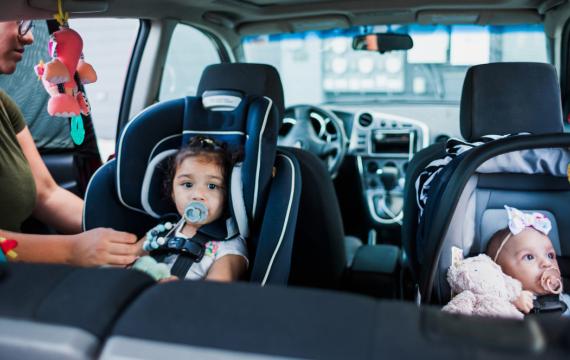 Mom safely buckling kids into their car seats following car seat safety guidelines