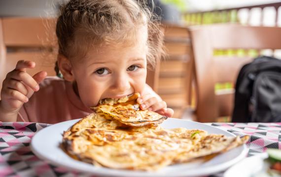 child eating potato and cheese gozleme on wooden table. Traditional stuffed pancakes in Alanya, Turkey. 