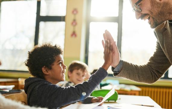 Boy and teacher giving a high five and have a positive student-teacher relationship