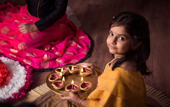 Girl celebrates Diwali Festival of Lights Around Seattle with diya and rangoli.