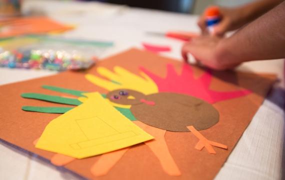 Child's hands making Thanksgiving turkey craft