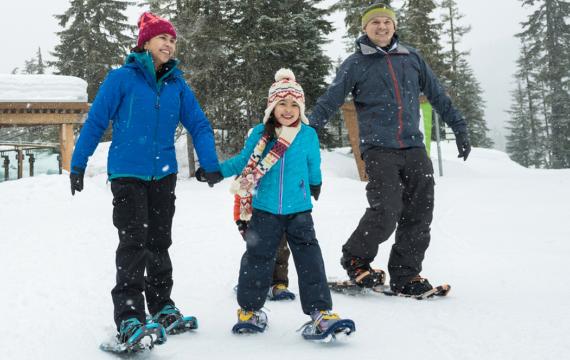 Twp parents and kids snowshoeing in the winter on a family adventure