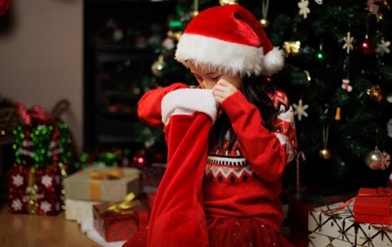 Girl looking in her Christmas stocking for the best stocking stuffers 