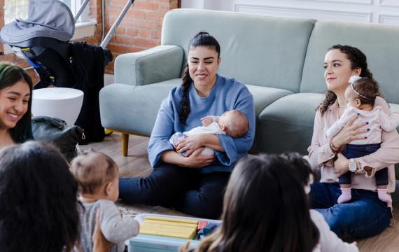 New moms sitting in a living room together connecting as new parents 