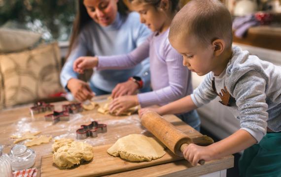 Children rolling out cookie dough for a holiday family tradition