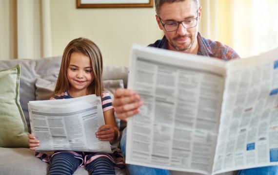 Dad and daughter reading the newspaper together