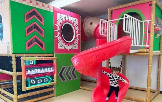 young girl sliding down bright slide at Little Pandas Play Cafe, a new indoor play place near Seattle