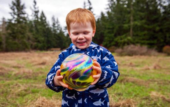 young child holding a glass float found during Northwest Glass Quest, a glass float hunt on Camano Island