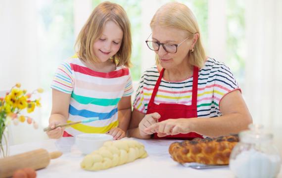 child and grandmother baking challah bread together