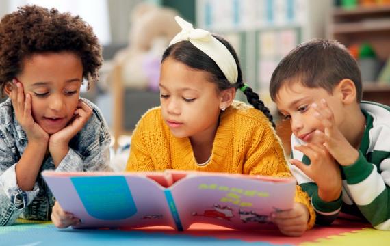 three kids on the floor reading a book together