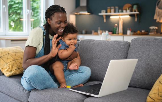 mom holding a baby waving to a computer call finding community online