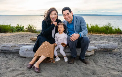 Seattle parents pose happily with their daughter on a Pacific Northwest beach
