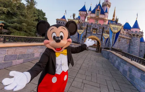 Mickey Mouse welcomes you to Disneyland in front of Sleeping Beauty's castle