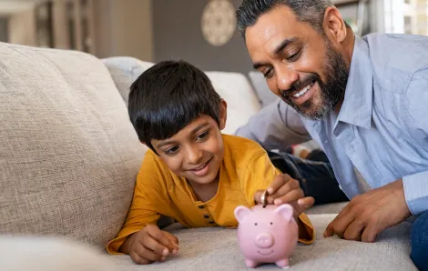 A dad and son learn about money management with a piggy bank
