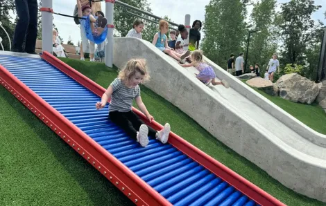 Young girl slides down a roller slide at a new inclusive playground near Seattle