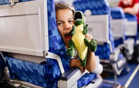 child plays with a toy on an airplane while traveling with family