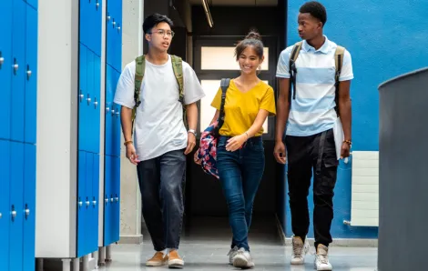 Three high school students walking down a school hallway