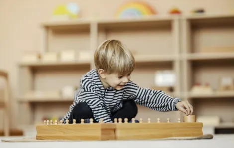 child plays in a Montessori playroom featuring low shelves and simple toys