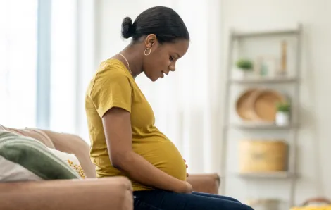 Pregnant woman looks down at her stomach