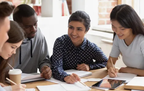 Teenagers sitting around a table with a teen girl as the leader