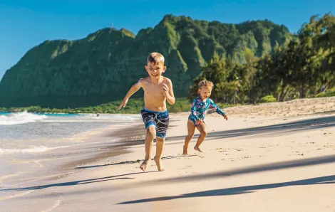 Two kids running on a beach Kauai family vacation things to do 