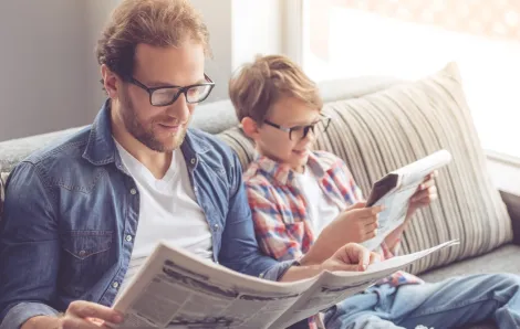 dad and son reading current events in the newspaper