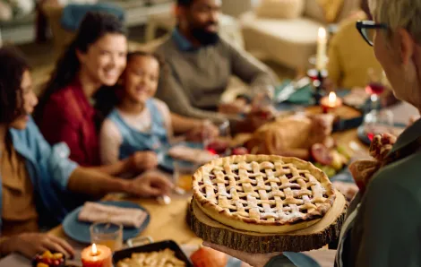 Family sitting around a dinner table with a pie coming for dessert