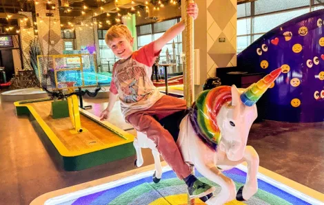 young child at putt putt mini golf course near Seattle on a rainy day, an indoor activity for families