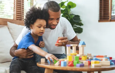 Dad and son having positive experience together playing with blocks on a table