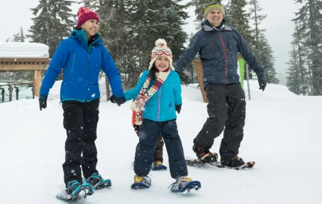 Twp parents and kids snowshoeing in the winter on a family adventure