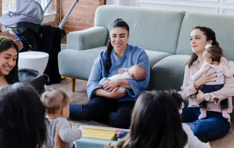 New moms sitting in a living room together connecting as new parents 