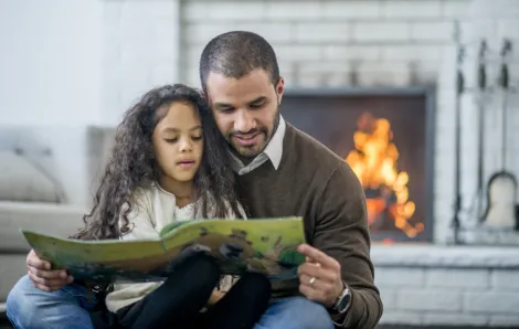 Dad and daughter reading in front of fireplace