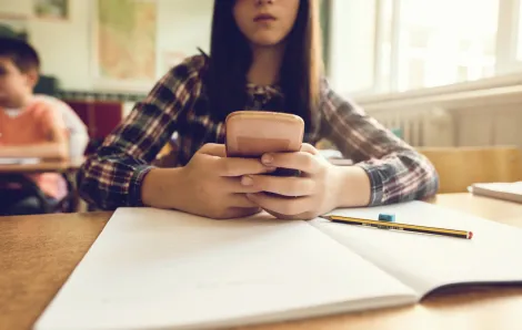 young student looks at her phone in class